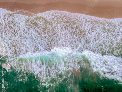 downward drone shot of waves crashing on beach