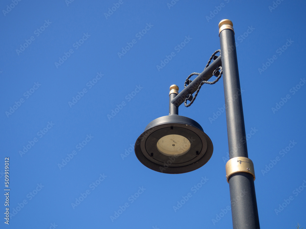 Black lantern against the blue sky. Interesting lamp design. Street lighting. Black lantern against the blue sky. Interesting lamp design. Street lighting.