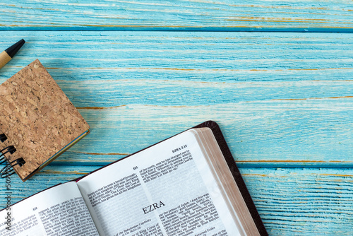 Fotografía Ezra open Holy Bible Book with a small notebook and pen on a rustic wooden background with copy space