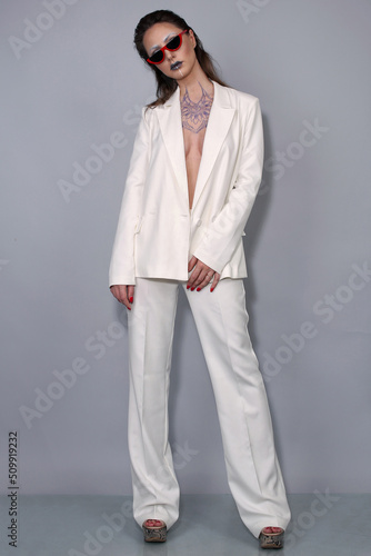Portrait of a beautiful fashion woman brunette in a white business suit in the studio in a glasses