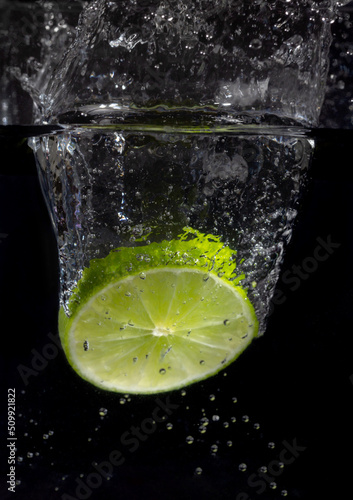 Lemon slice in water, splash photography. Dark background.