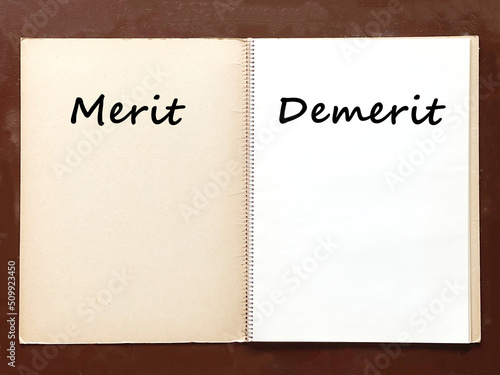 机の上で開いた古いスケッチブックにMeritとDemeritの文字