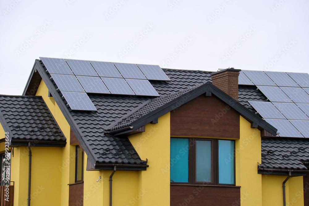 Residential house with rooftop covered with solar photovoltaic panels for producing of clean ecological electrical energy in suburban rural area. Concept of autonomous home Residential house with rooftop covered with solar photovoltaic panels for producing of clean ecological electrical energy in suburban rural area. Concept of autonomous home