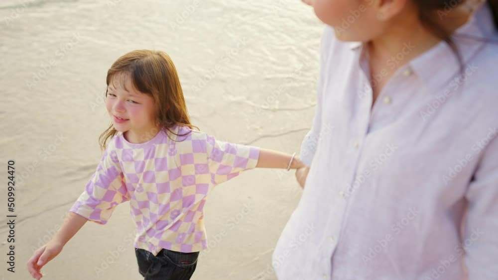 Happy Asian family on beach vacation. Mother and little daughter walking and playing together on tropical beach at summer sunset. Mom and child girl kid enjoy and fun outdoor lifestyle on the beach