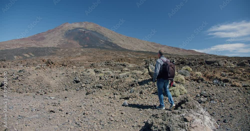 Tourist with camera takes a picture of mountain. Hiker backpacker walks and films amazing view of mount Guajara and volcano el Teide, Tenerife, Canary Islands Tourist with camera takes a picture of mountain. Hiker backpacker walks and films amazing view of mount Guajara and volcano el Teide, Tenerife, Canary Islands