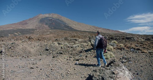 Tourist with camera takes a picture of mountain. Hiker backpacker walks and films amazing view of mount Guajara and volcano el Teide, Tenerife, Canary Islands photo