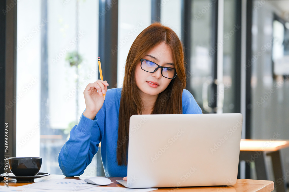 Young female college student uses a computer to access the Internet for online learning. Young female college student uses a computer to access the Internet for online learning.