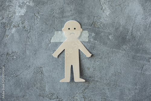 Фотография Photo of concept of illegal deprivation of rights of child, paper cut sad man sticking with adhesive tape on gray smeared plaster wall