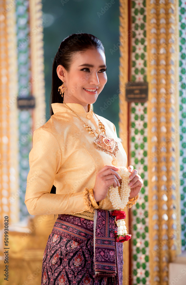 Portrait of young Asian women in traditional Thai costumes worshiping Buddha images with flower garlands. Preserving the good culture of Thai people during Songkran Festival, Thai New Year, April Fami