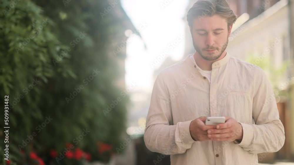 Close up of attractive man hold smartphone, watching social media standing on a city street. Smiling young guy texting on her phone. Close up of attractive man hold smartphone, watching social media standing on a city street. Smiling young guy texting on her phone.