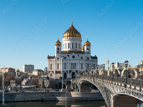 Moscow, Russia - March 01, 2022: View of the Cathedral of Christ the Savior and the Patriarchal pedestrian bridge against the blue sky