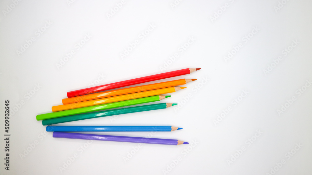 Fototapeta premium colored pencils in row on a white background top view.