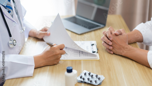 Visiting a doctor concept A doctor rating health condition of his patient while listening to his patient’s symptom. photo