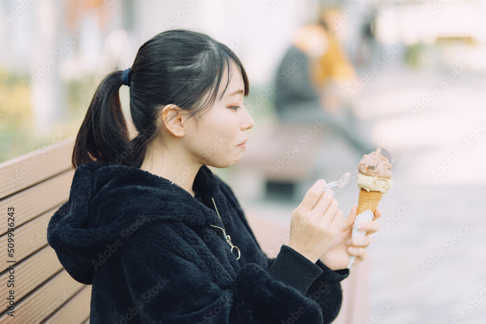 愛知県名古屋市久屋大通公園でジェラートを笑顔で食べる若い女性 Young woman smiling and eating gelato in Hisaya-odori Park, Nagoya, Aichi, Japan. 