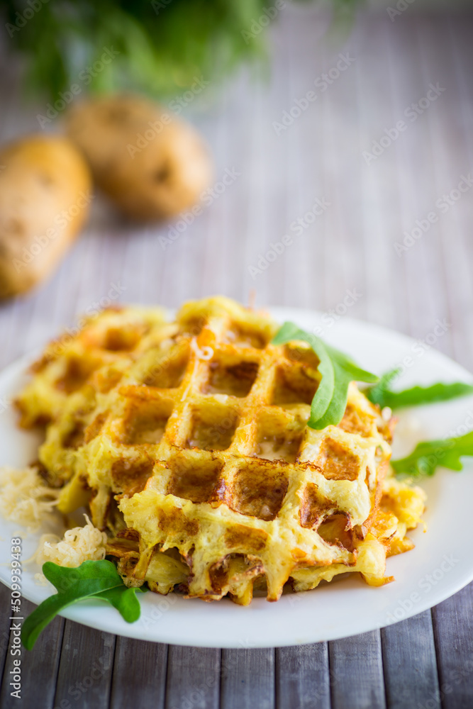 fried potato waffles with cheese in a plate on wooden table. fried potato waffles with cheese in a plate on wooden table.
