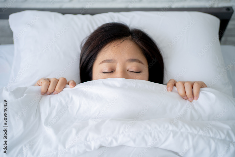 Cozy bedclothes. Asian girl hiding under blanket in bed, top view Cozy bedclothes. Asian girl hiding under blanket in bed, top view