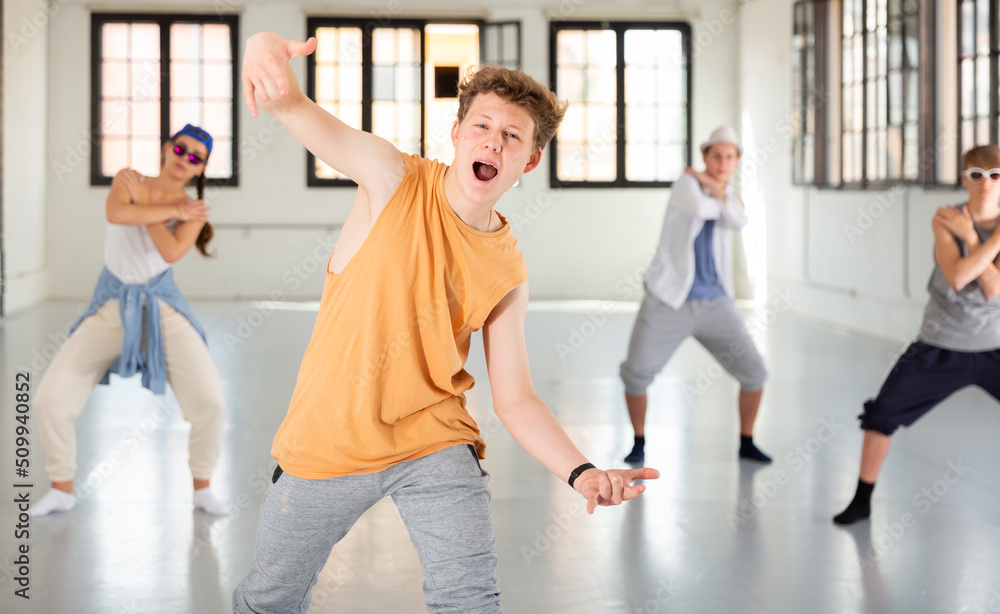 Portrait of teenage boy performing hip hop elements at group dance training in studio