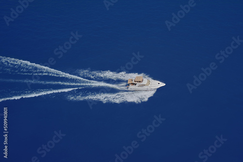 Speed boat movement at high speed aerial view. High-speed yacht of white color fast motion on blue water in the rays of the sun top view.