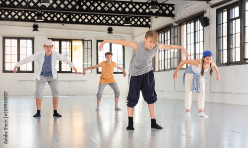 Group of teenagers training at dance class, practicing contemporary dance moves