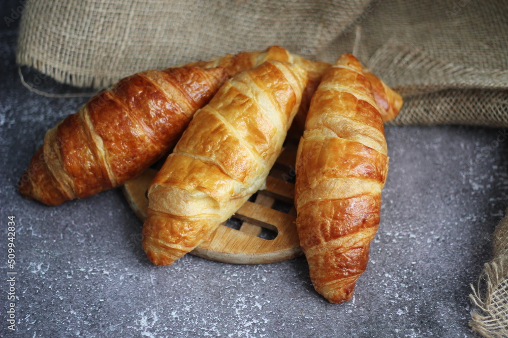 Croissant bread stacked on the table with wooden plates and sackcloth. Croissant bread stacked on the table with wooden plates and sackcloth.