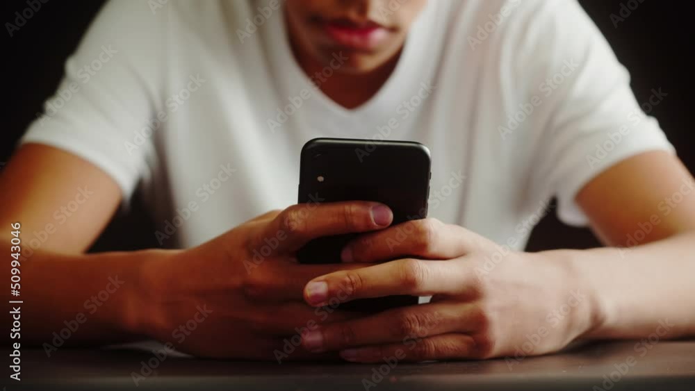 African American man using smartphone. Young guy texting at phone, teenager relaxing at home. Communicating with family and friends online, sitting on sofa in living room. African American man using smartphone. Young guy texting at phone, teenager relaxing at home. Communicating with family and friends online, sitting on sofa in living room.