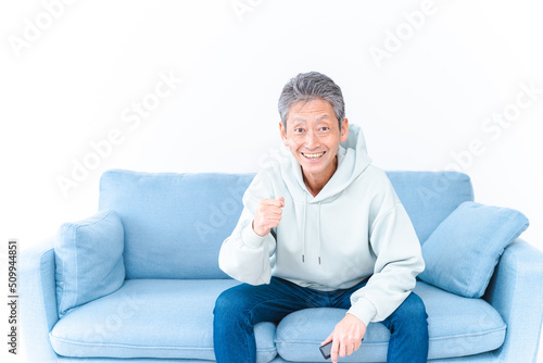自宅のテレビでスポーツ観戦をする高齢の男性 © maroke