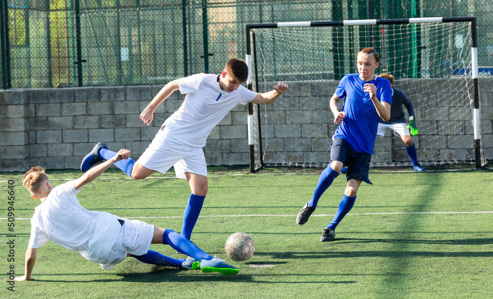 Fototapeta premium Teens playing soccer football match. Competition between two youth soccer teams. Football soccer tournament