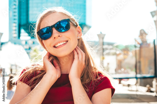 Young beautiful smiling hipster woman in trendy summer clothes. Sexy carefree woman posing on the street background at sunset. Positive model outdoors. Cheerful and happy in sunglasses
