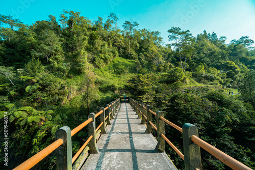 Fototapeta Naklejka Na Ścianę i Meble -  Iconic bridge in one of the tourist destinations in Kali Kuning, Sleman, Indonesia with green hills in the morning