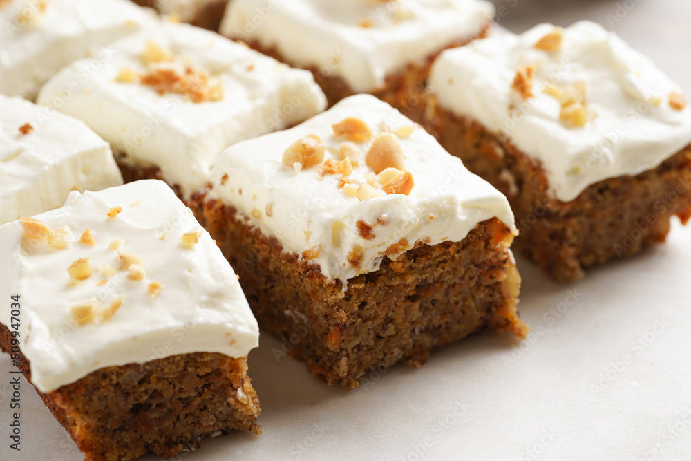 Homemade pastry carrot-walnut cake with grounded almonds and hazelnuts and white cream cheese top layer on marble board