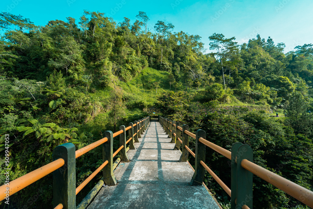 Iconic bridge in one of the tourist destinations in Kali Kuning, Sleman, Indonesia with green hills in the morning