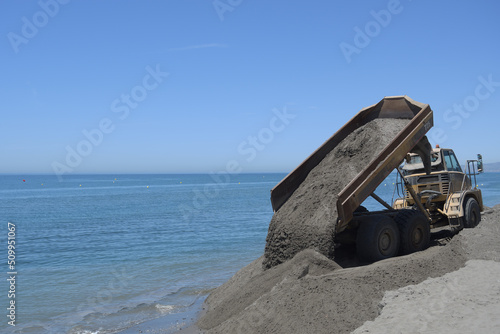 Truck depositing sand in a beach a summer day