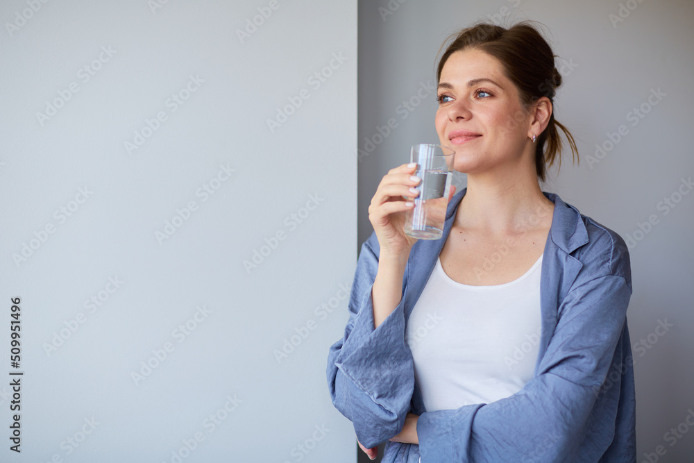Happy smiling woman wearing pajamas holding water or some drink in glass. Happy smiling woman wearing pajamas holding water or some drink in glass.