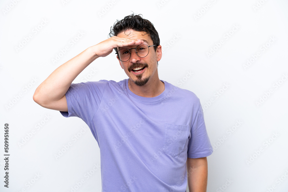 Young man with moustache isolated on white background looking far away with hand to look something Young man with moustache isolated on white background looking far away with hand to look something