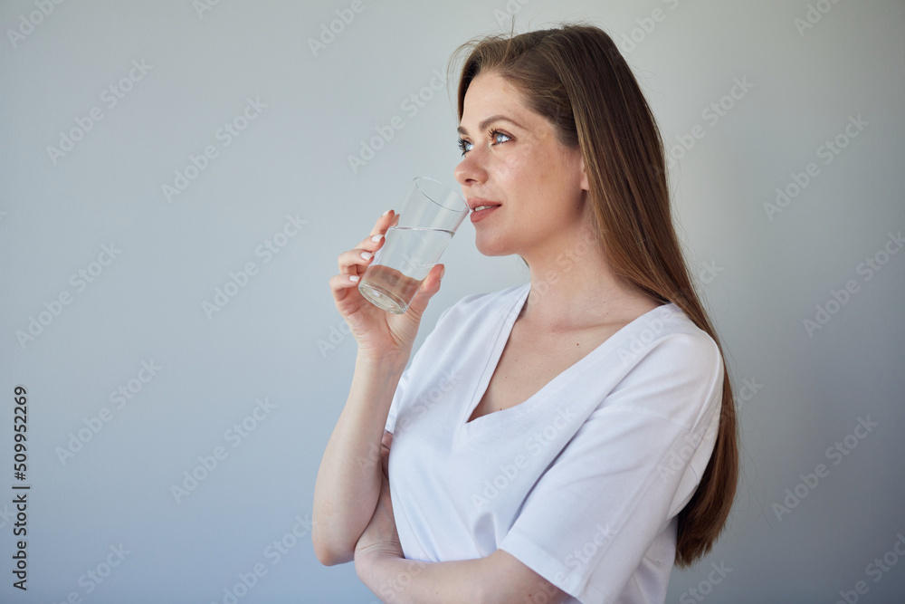 Woman drinking water looking away. isolated portrait of girl wearing white shirt. Woman drinking water looking away. isolated portrait of girl wearing white shirt.
