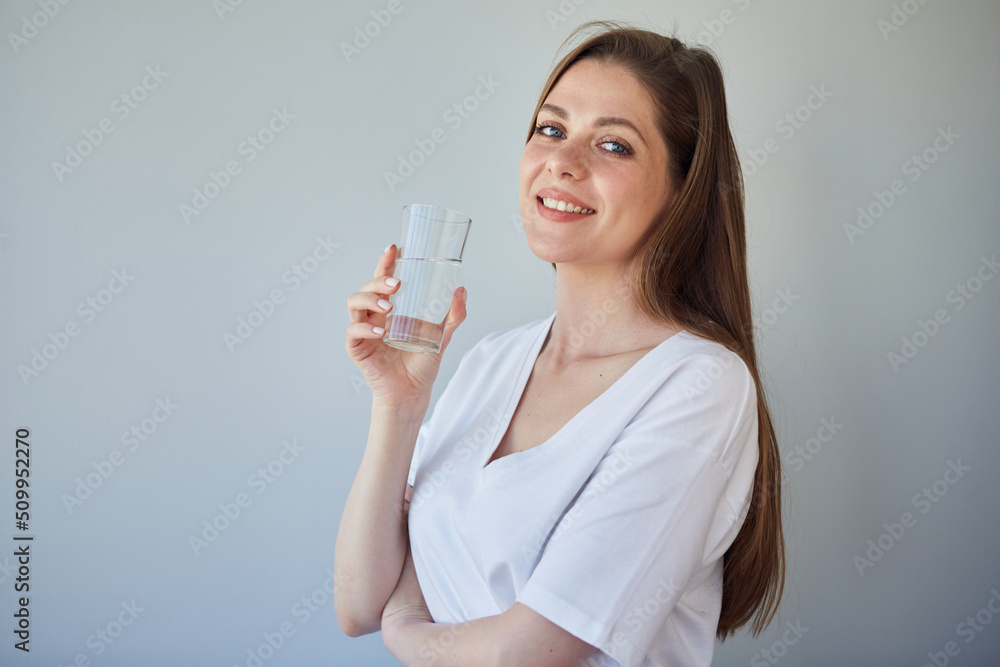 Smiling woman holding water glass. isolated portrait of girl wearing white shirt. Smiling woman holding water glass. isolated portrait of girl wearing white shirt.