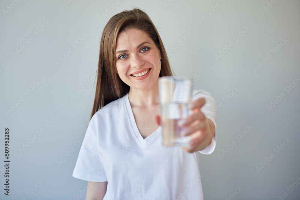 Smiling woman holding water glass. isolated portrait of girl wearing white shirt. Smiling woman holding water glass. isolated portrait of girl wearing white shirt.