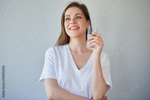 Woman drinking water looking away. isolated portrait of girl wearing white shirt.