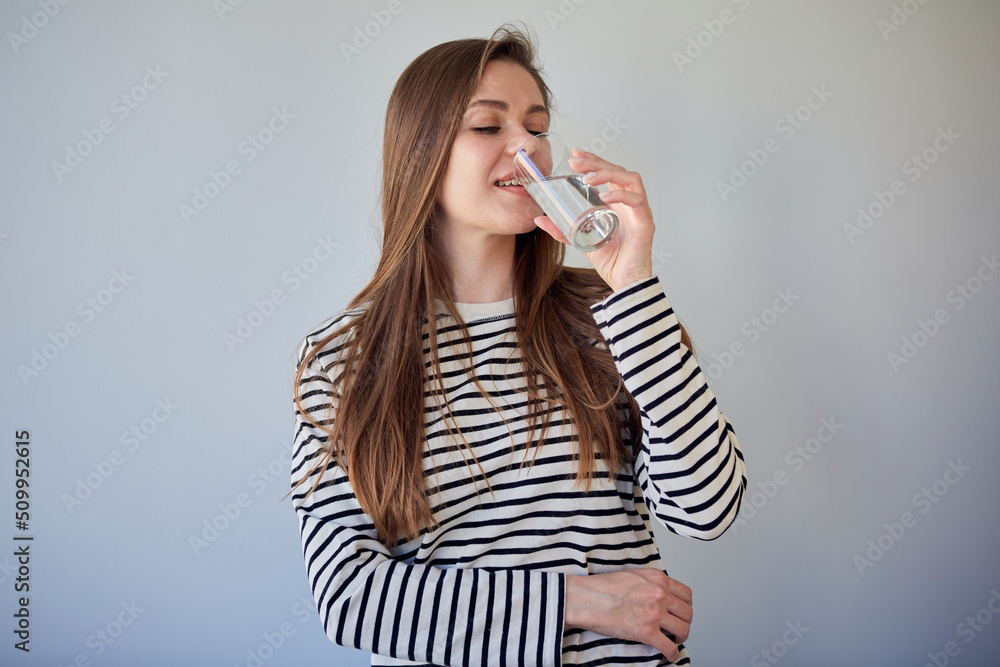 Woman drinking water looking away. isolated portrait happy girl. Woman drinking water looking away. isolated portrait happy girl.