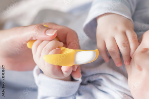 male baby holds banana teether in his hand, development and massage of the gums. close up teether