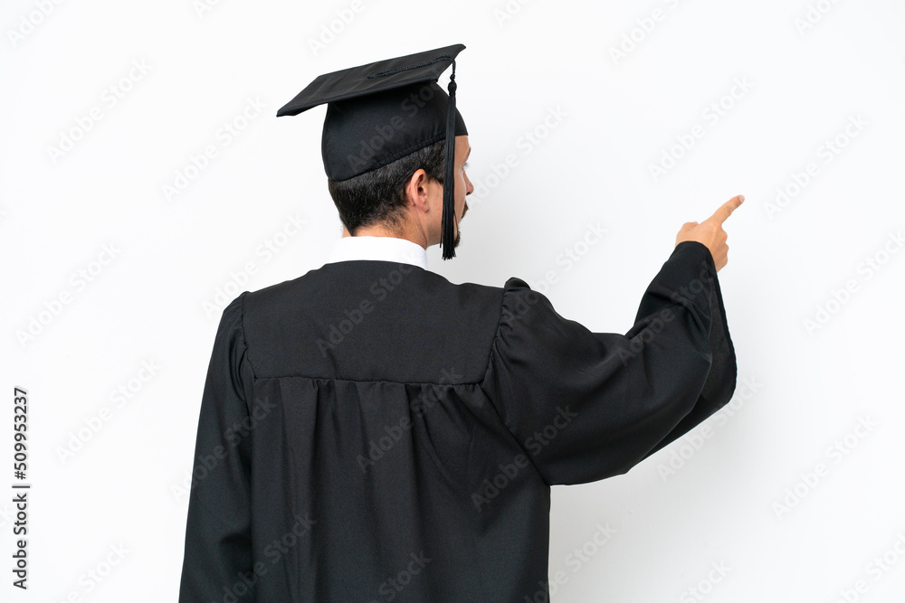 Young university graduate man isolated on white background pointing back with the index finger Young university graduate man isolated on white background pointing back with the index finger