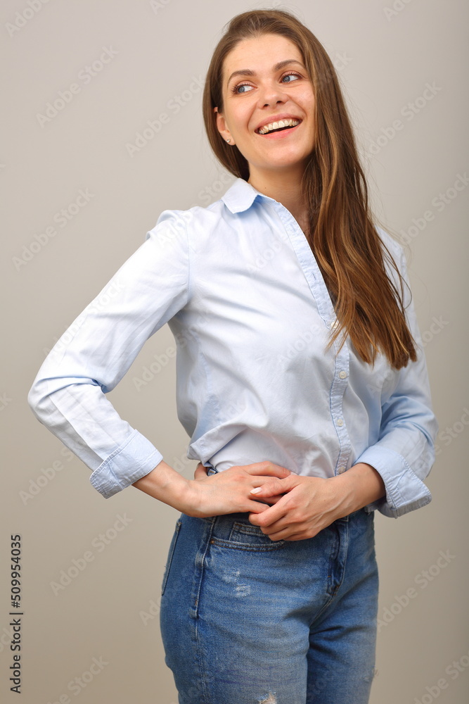 Smiling woman in blue shirt looking back over shoulder and keeps her arms on hip. isolated portrait. Smiling woman in blue shirt looking back over shoulder and keeps her arms on hip. isolated portrait.