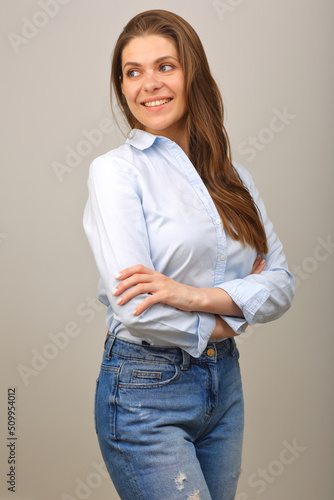 Smiling woman in blue shirt looking back over shoulder and keeps her arms crossed. isolated portrait.
