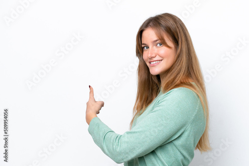 Young caucasian woman isolated on white background pointing back