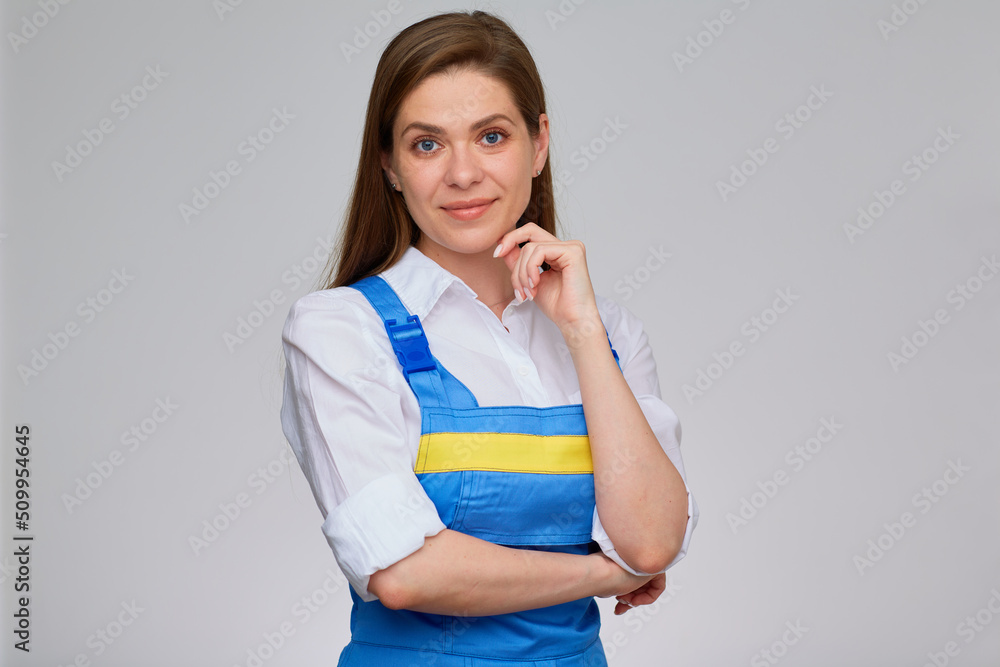 Young smiling woman in blue overall uniform and white shirt standing against isolated back. Young smiling woman in blue overall uniform and white shirt standing against isolated back.