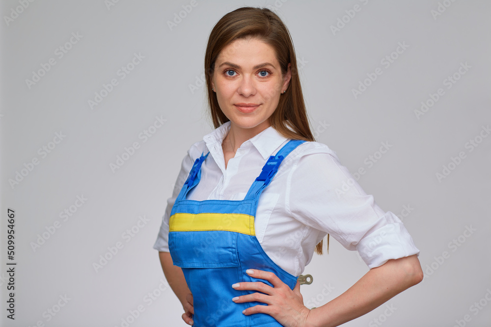 Woman in blue overall uniform and white shirt hard work style portrait with girl keeps her hands on hips. Woman in blue overall uniform and white shirt hard work style portrait with girl keeps her hands on hips.