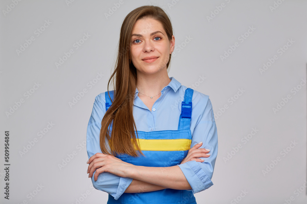 Smiling woman worker plumber or elictrician in blue overalls with yellow stripe standing with arms crossed. isolated portrait of happy girl with long hair. Smiling woman worker plumber or elictrician in blue overalls with yellow stripe standing with arms crossed. isolated portrait of happy girl with long hair.
