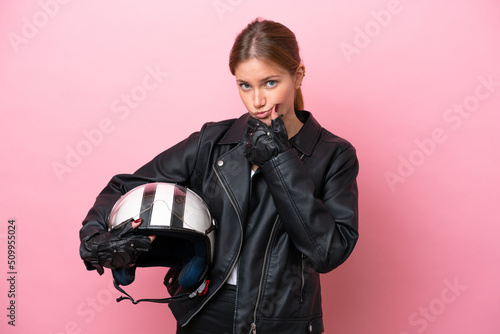 Young caucasian woman with a motorcycle helmet isolated on pink background thinking