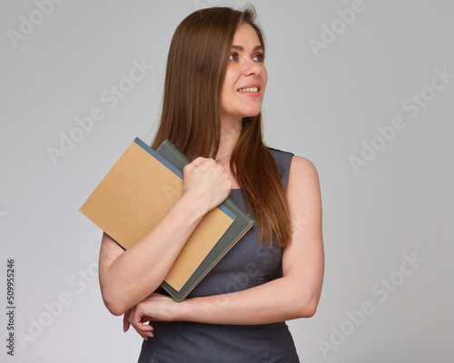 Female teacher with long hair in business dress holding books and looking away. Isolated portrait. © Yuriy Shevtsov