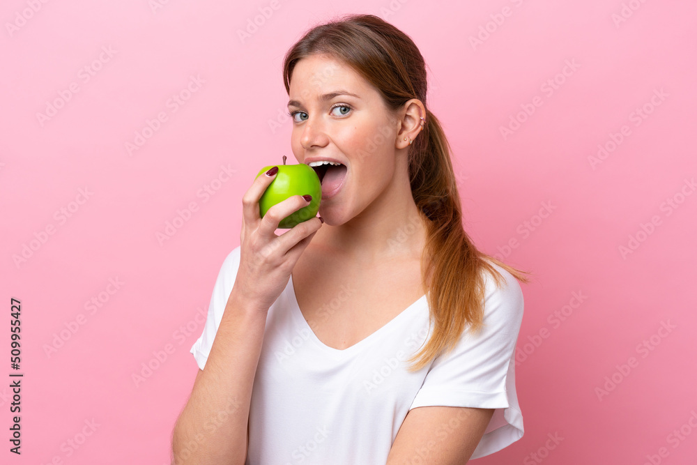 Young caucasian woman isolated on pink background eating an apple Young caucasian woman isolated on pink background eating an apple